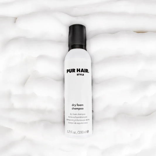 PUR HAIR Style Dry Foam Shampoo – weiße Flasche mit schwarzem Deckel, liegend auf fluffigem Schaum-Hintergrund, für frisches Haar ohne Waschen