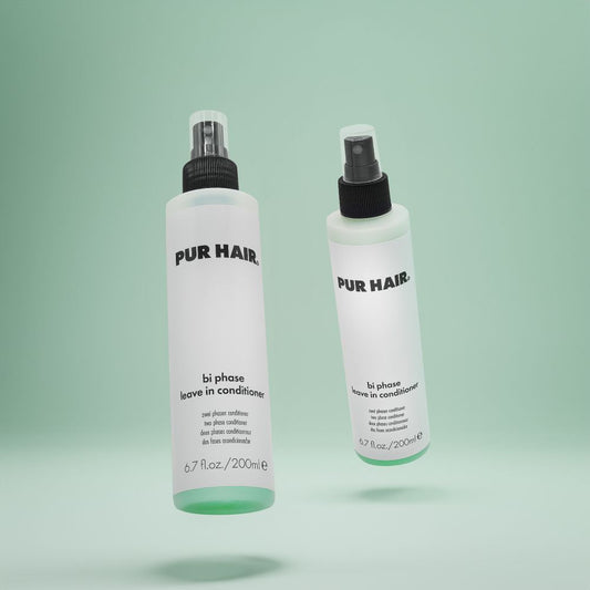Zwei Flaschen PUR HAIR Bi Phase Leave-in Conditioner, 200 ml, mit Sprühkopf vor grünem Hintergrund