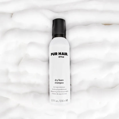 PUR HAIR Style Dry Foam Shampoo – weiße Flasche mit schwarzem Deckel, liegend auf fluffigem Schaum-Hintergrund, für frisches Haar ohne Waschen
