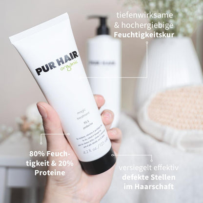 PUR HAIR Organic Magic Treatment in 125 ml Tube wird in der Hand gehalten, im Hintergrund weiße Blüten und eine große Flasche; Text weist auf Feuchtigkeitspflege, 80 % Feuchtigkeit, 20 % Proteine, versiegelt effektiv defekte Stellen am Haar