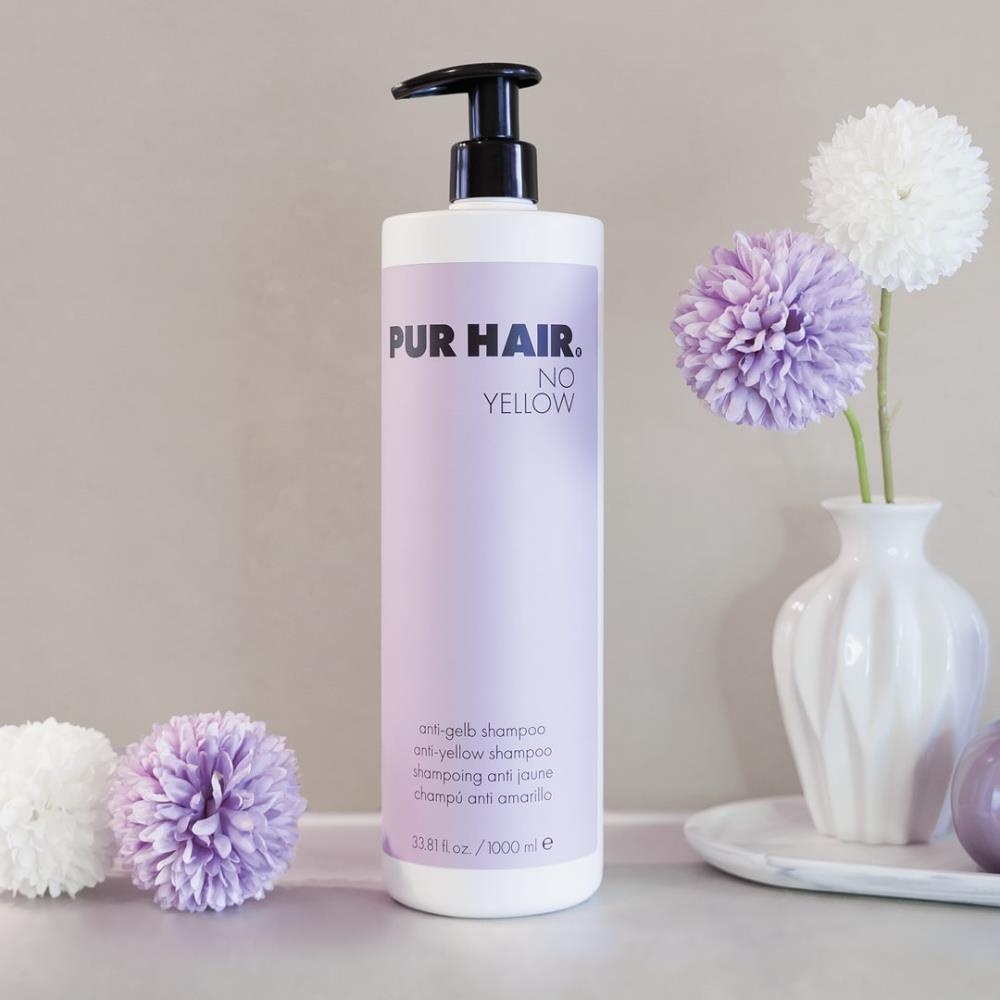 Weiße Flasche PUR HAIR No Yellow Shampoo, 1000 ml, neben violetten Trockenblumen im Badezimmer platziert
